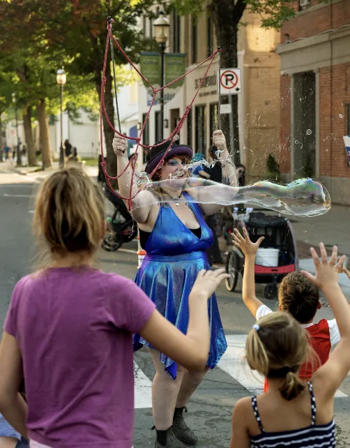 A bubble performer making giant soap bubbles for children on the street at Harvest