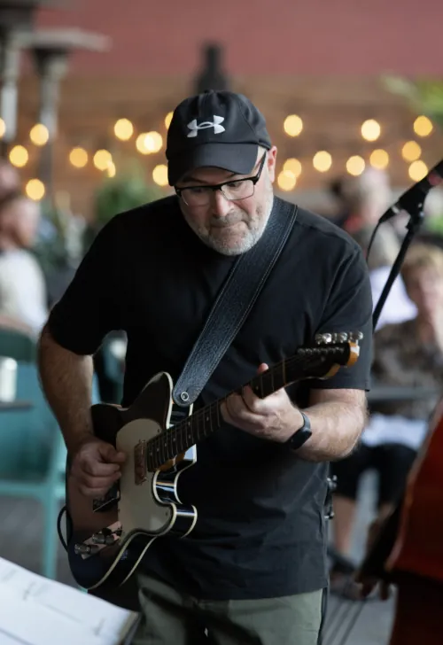 A guitarist playing under string lights at a Harvest street show