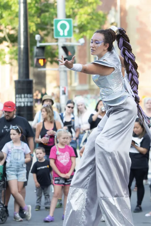 A silver-costumed stilt-walker performing for families in the Garrison District at Harvest